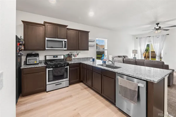 a kitchen with kitchen island granite countertop a sink stainless steel appliances and white cabinets