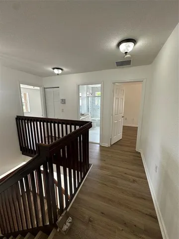 a view of a hallway with wooden floor and staircase