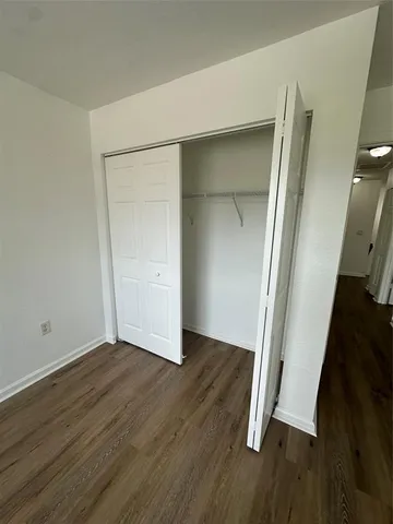 an empty room with wooden floor and closet