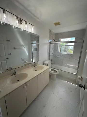 a bathroom with a granite countertop sink mirror and toilet