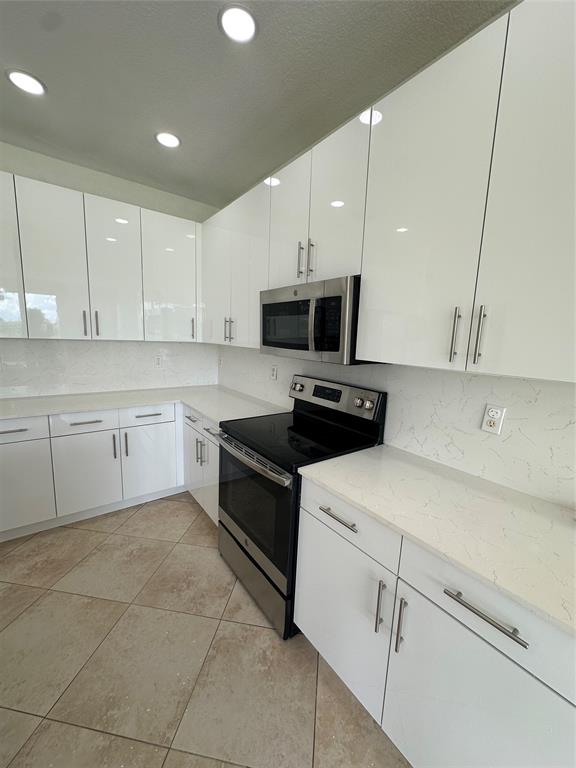 13376 Southwest 47th Street Miramar, FL 33027 - Photo 8 of 38 a kitchen with stainless steel appliances a stove a sink and a refrigerator