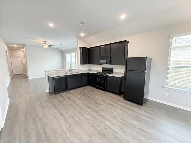 a large kitchen with stainless steel appliances granite countertop a refrigerator and a stove top oven