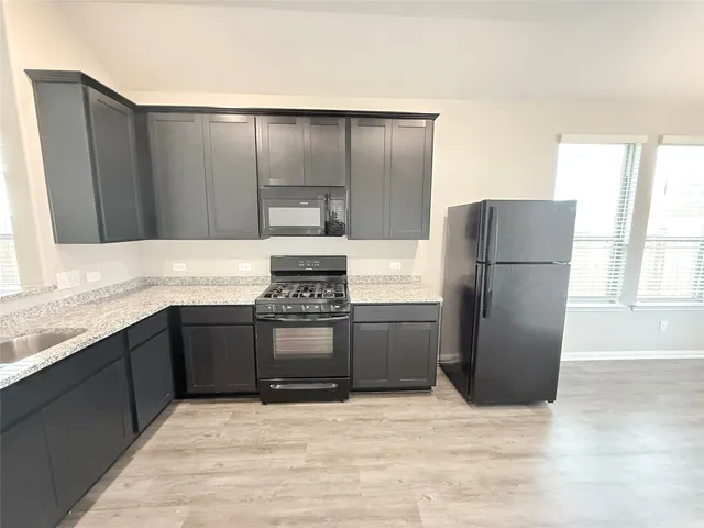 a kitchen with stainless steel appliances granite countertop a refrigerator and a stove top oven