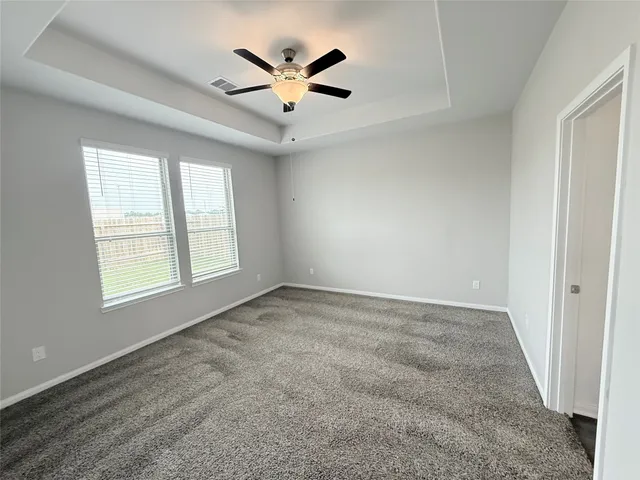 an empty room with windows and ceiling fan