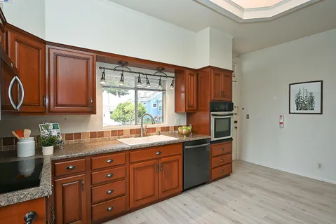 a kitchen with stainless steel appliances granite countertop wooden cabinets a sink and dishwasher with wooden floor