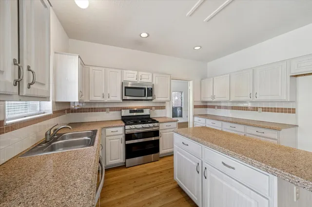 a kitchen with granite countertop a sink stainless steel appliances and cabinets