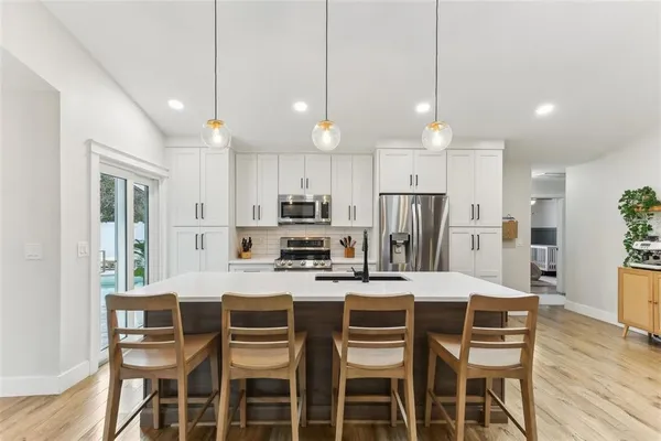 a kitchen with stainless steel appliances a dining table chairs refrigerator and microwave