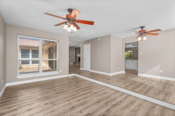 a view of an empty room with wooden floor and a window
