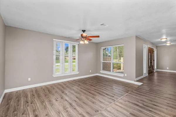 a view of an empty room with wooden floor and a fireplace
