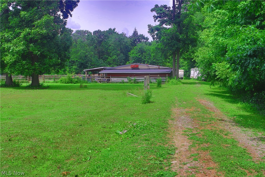 7250 Brakeman Road Painesville, OH 44077 - Photo 4 of 17 Expansive grassy area featuring a gravel path, mature trees, and a distant outbuilding with a red roof