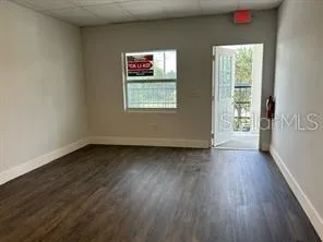 a view of an empty room with wooden floor and a window