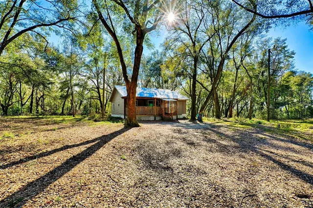 a backyard of a house with large trees and a wooden fence
