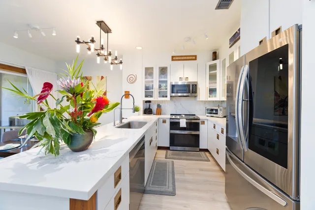 a kitchen with stainless steel appliances kitchen island granite countertop a refrigerator a stove and a sink