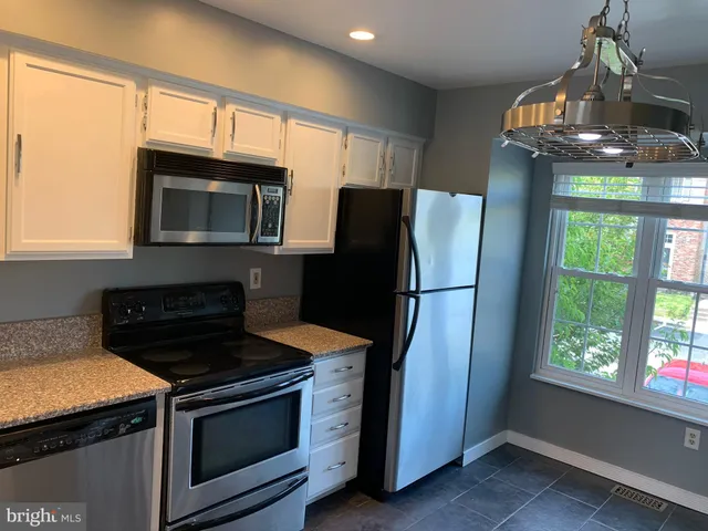 a kitchen with granite countertop a refrigerator stove and microwave