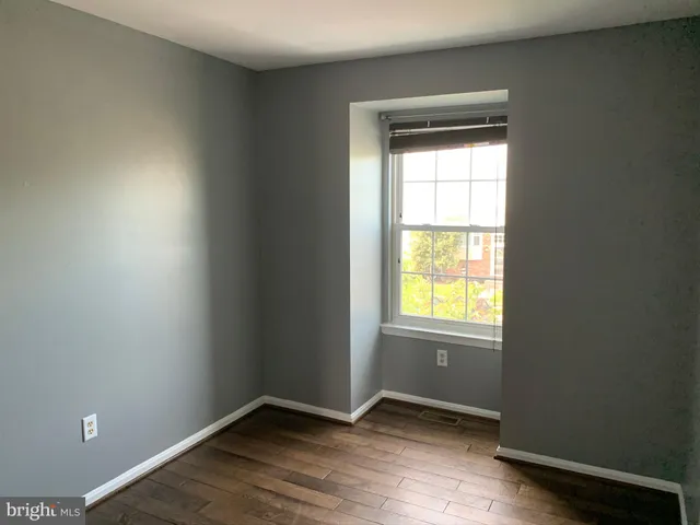 an empty room with wooden closet and windows