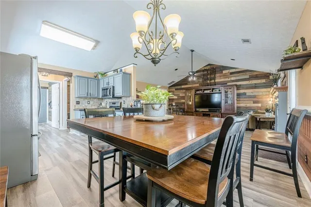 a kitchen with stainless steel appliances granite countertop a stove top oven a sink dishwasher a dining table and chairs with wooden floor