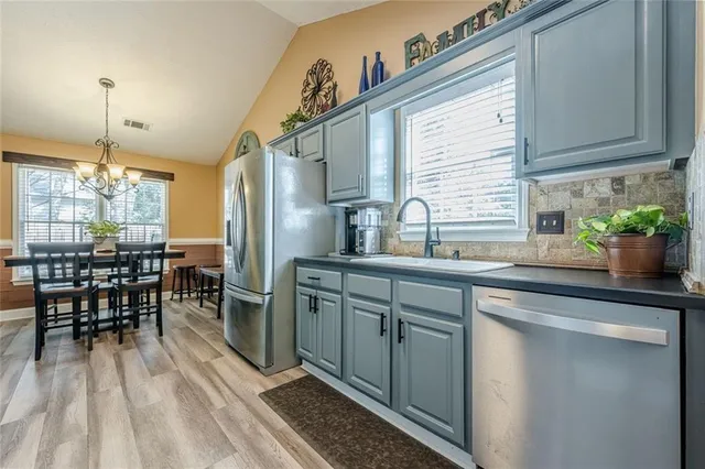 a kitchen with stainless steel appliances granite countertop a refrigerator a stove and a sink with wooden floors
