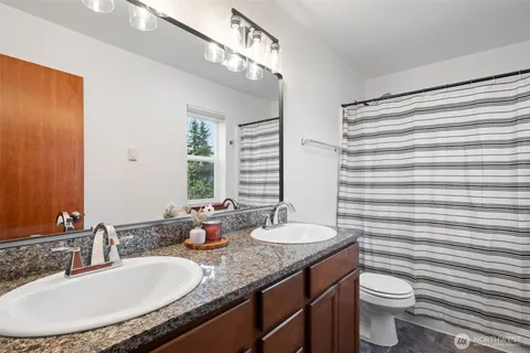 a bathroom with a granite countertop sink toilet and mirror