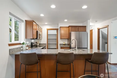 a kitchen with granite countertop a stove a sink and a refrigerator
