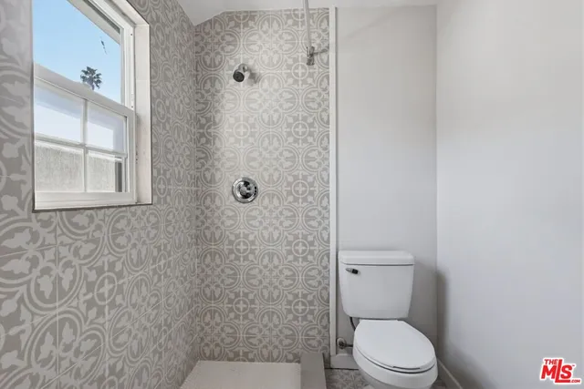a white toilet sitting next to a bathroom sink and a shower