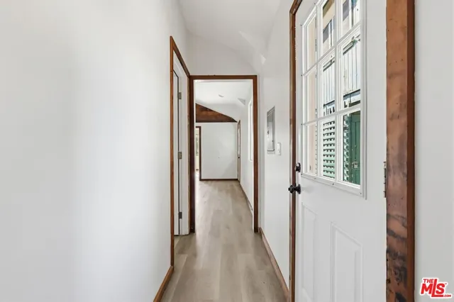 a view of a hallway with wooden floor and a bathroom