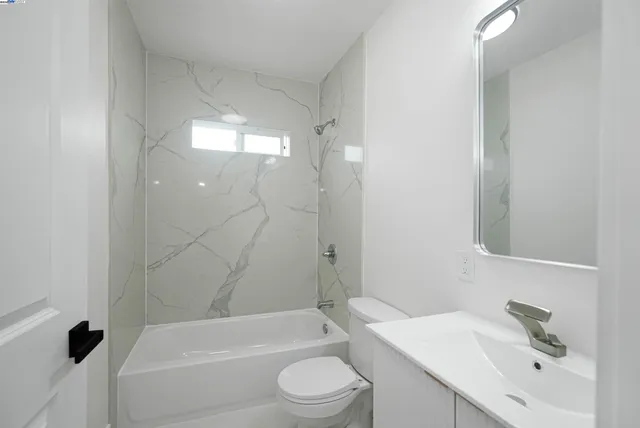 a bathroom with a bathtub shower sink vanity mirror and toilet