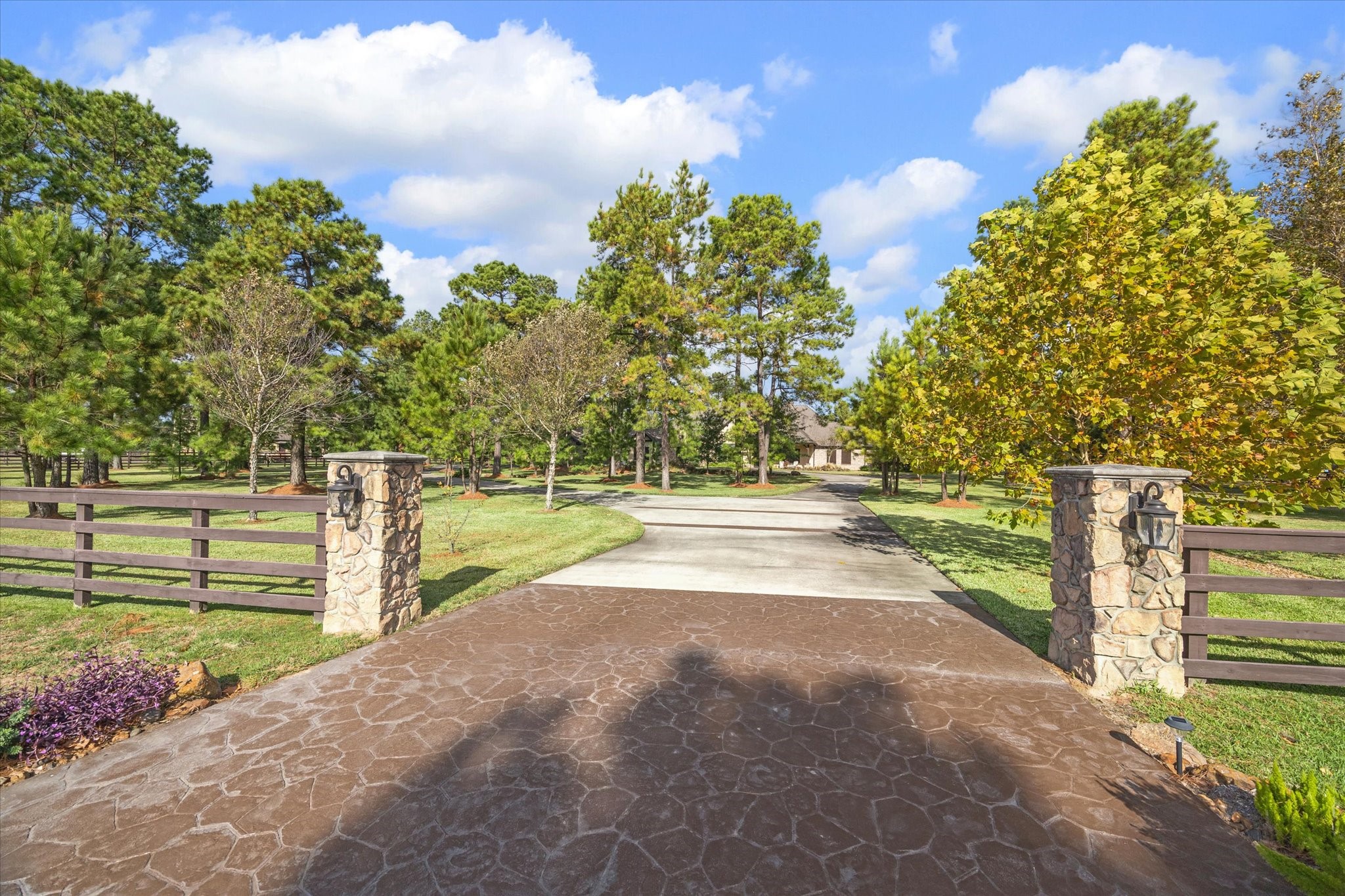 11 Willowcreek Ranch Road Tomball, TX 77377 - Photo 5 of 49 The entrance to the estate is demarked with stone columns and lighted coach lanterns, revealing but a glimpse of the sprawling property beyond. The estate boasts a circular driveway, on one side leading to additional parking near the front entrance while the other side leads to the porte-cochere, motor court, garages and barn. The width of the entrance and the depth of the concrete pour was designed to accommodate the access, weight and width of horse trailers and large RVs.