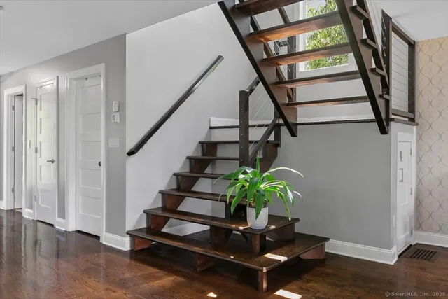 a living room with wooden floor stairs and a potted plant