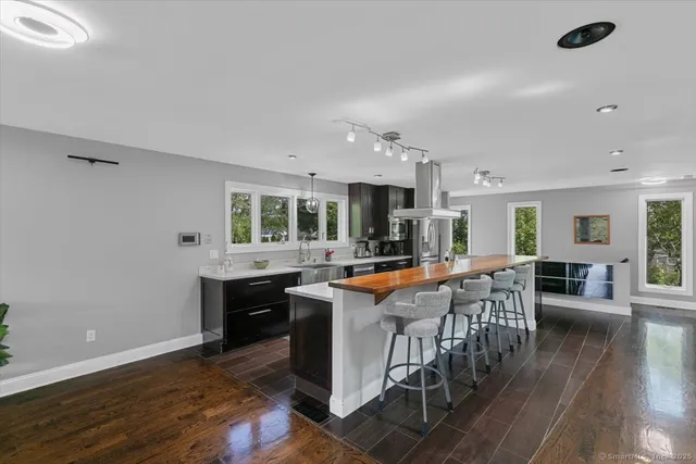 a kitchen with stainless steel appliances granite countertop a table chairs sink and cabinets
