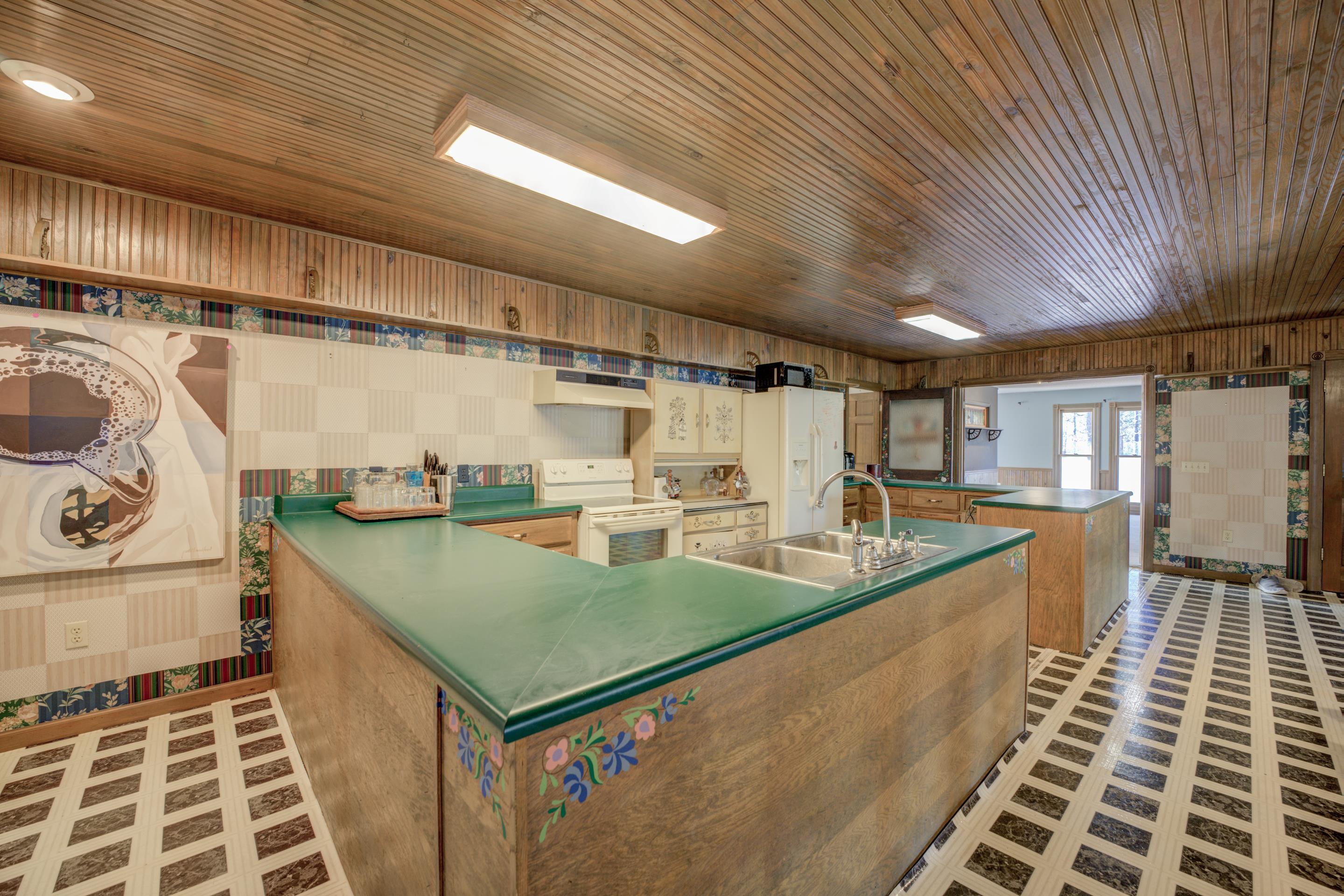 183 Matlock Road Ramer, TN 38367 - Photo 13 of 34 a view of a kitchen with kitchen island a stove a chimney a sink and wooden cabinets