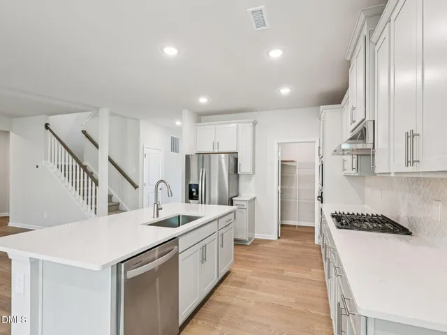 a living room with furniture wooden floor and a kitchen view