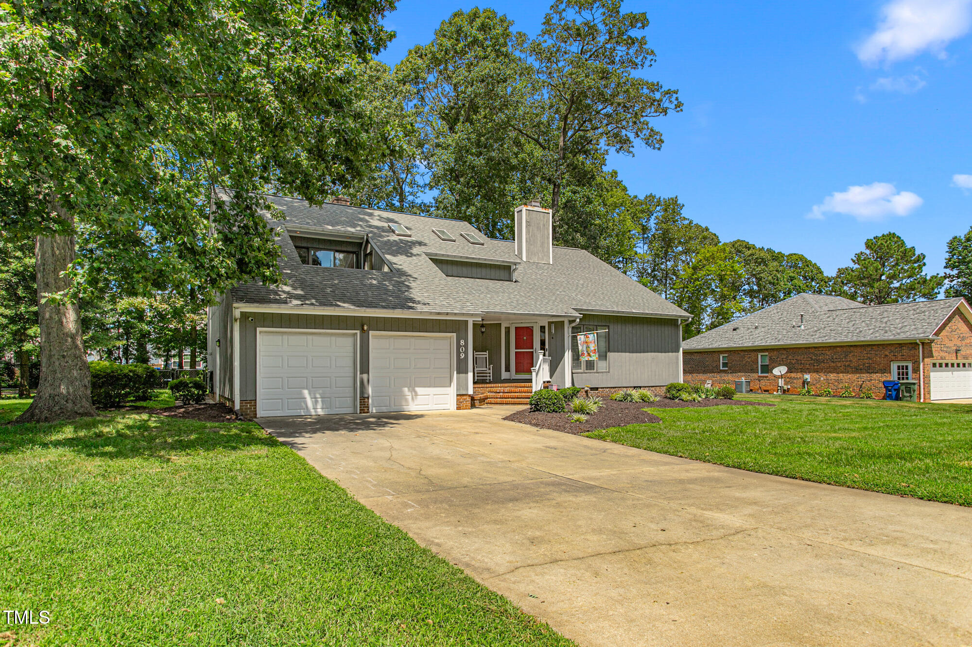 809 Brookview Drive Elon, NC 27244 - Photo 3 of 53 a front view of a house with a garden and trees