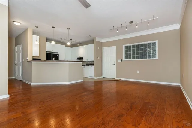 a view of a kitchen with kitchen island a sink wooden floor and stainless steel appliances