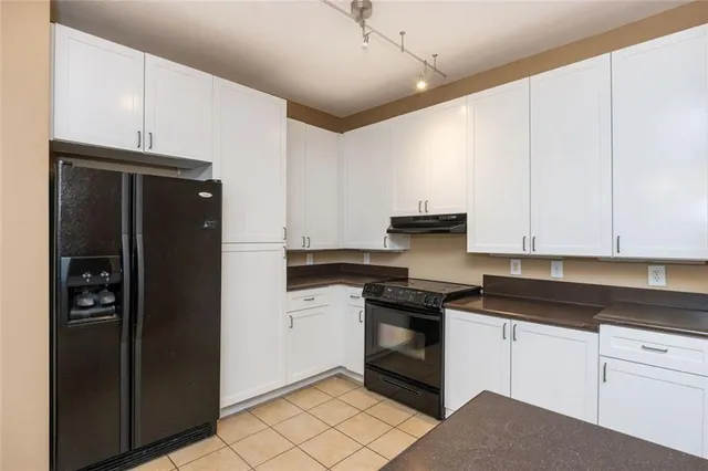 a kitchen with a refrigerator and white cabinets