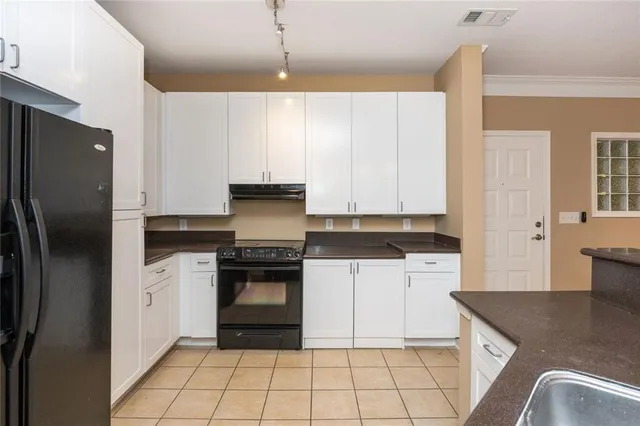 a kitchen with stainless steel appliances granite countertop a refrigerator a stove and white cabinets with wooden floors