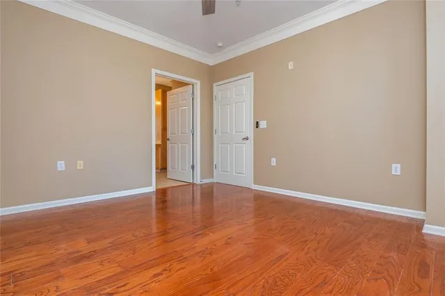 a view of an empty room with wooden floor and closet