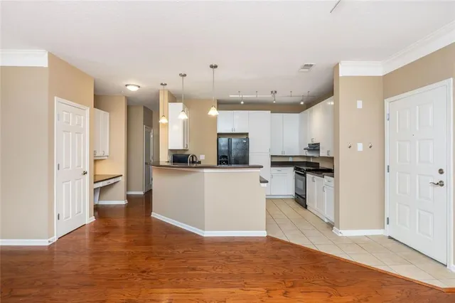 a view of kitchen with refrigerator stove and white cabinets