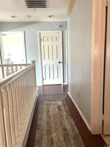 a view of a hallway with wooden floor and staircase
