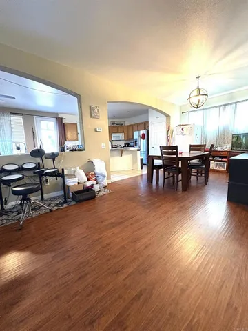 a living room with furniture and a dining table with wooden floor