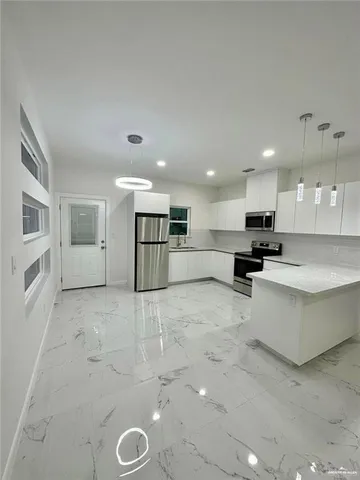a large white kitchen with a large window and stainless steel appliances
