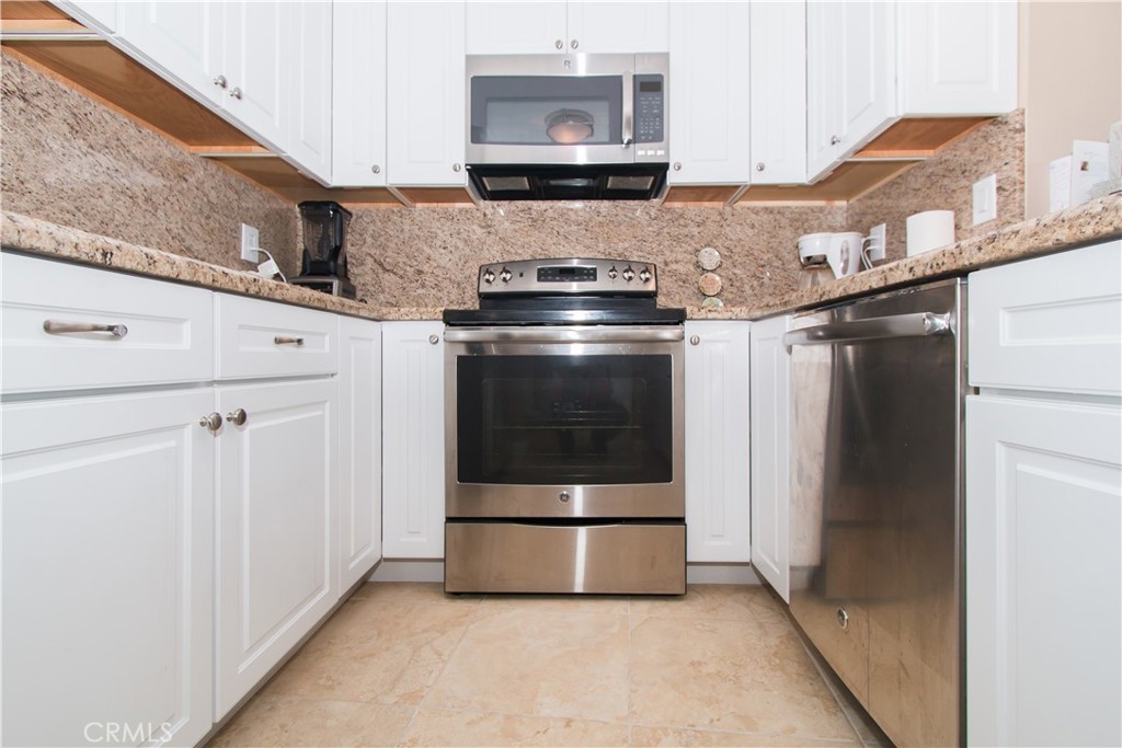 700 East Ocean Boulevard, Unit 706 Long Beach, CA 90802 - Photo 12 of 31 a kitchen with granite countertop white cabinets and stainless steel appliances