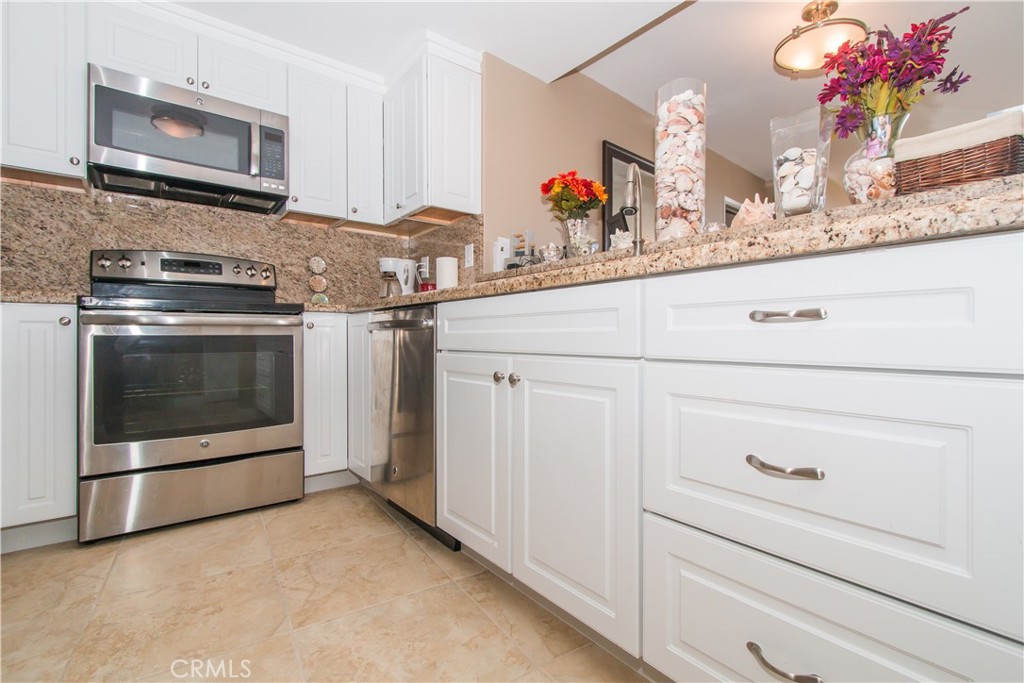 700 East Ocean Boulevard, Unit 706 Long Beach, CA 90802 - Photo 15 of 31 a kitchen with granite countertop white cabinets stainless steel appliances and a sink