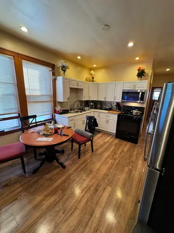 a living room with stainless steel appliances furniture a rug and a kitchen view