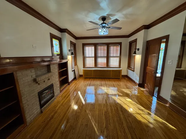 a view of an empty room with a fireplace and wooden floor