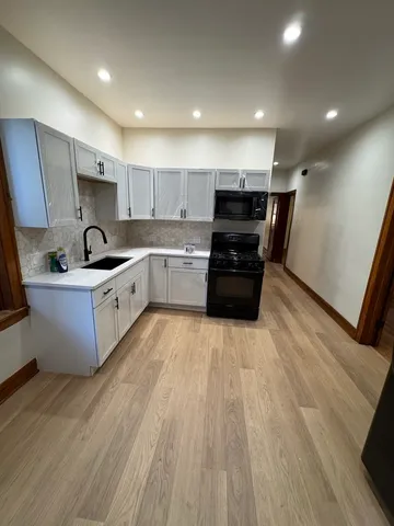 a kitchen with kitchen island granite countertop a sink and wooden cabinets