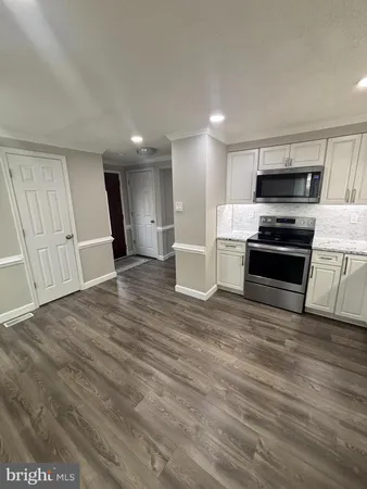 a view of kitchen with kitchen island wooden floor and stainless steel appliances