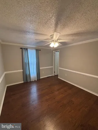 an empty room with wooden floor fan and window