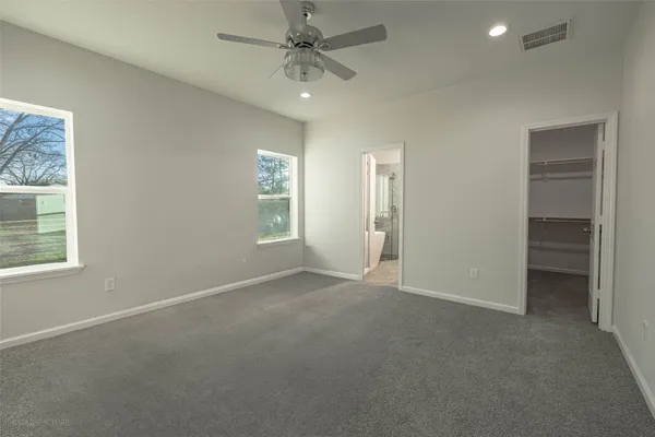 an empty room with windows and fan