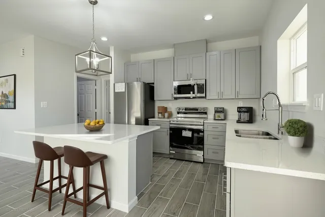 a kitchen with stainless steel appliances a stove a sink a refrigerator a center island and a window