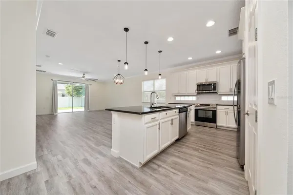 a kitchen with stainless steel appliances granite countertop a sink a stove and a wooden floor